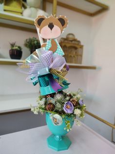 a blue vase filled with flowers and a teddy bear decoration on top of it's head