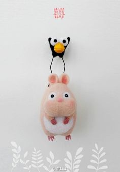 a stuffed animal hanging from the side of a wall with two small birds on it's back