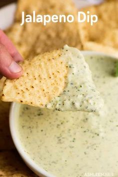 a tortilla chip being dipped with jalapeno dip