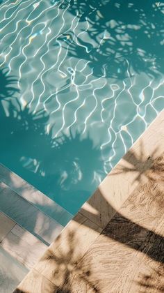 an empty swimming pool with water reflecting off the floor and shadows on the wall behind it