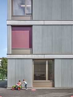 two children are playing in front of a building with purple and white stripes on it