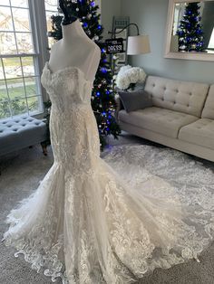 a wedding dress on display in front of a christmas tree