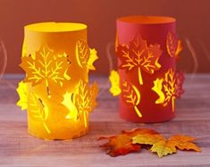 three lit candles sitting on top of a wooden table next to leaves and acorns