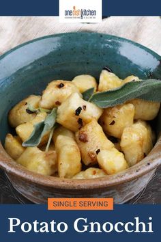 a blue bowl filled with potatoes and sage