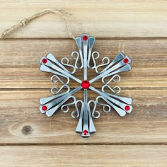 a snowflake ornament hanging on a wooden surface with red beads and twine