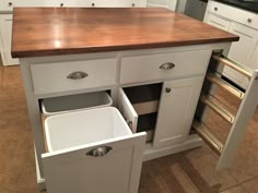 a kitchen island with two pull out bins in the middle and an open drawer