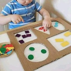 a little boy that is sitting in front of a box with some cut outs on it