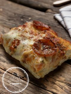 a slice of pepperoni pizza sitting on top of a wooden table next to a napkin