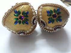 two gold and green brooches sitting on top of a white table next to each other