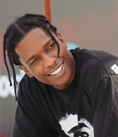 a young man with dreadlocks smiles while holding a baseball bat in his hand