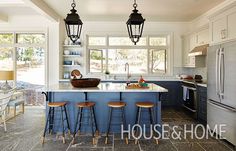 a kitchen with blue cabinets and counter tops, two hanging lights over the island area