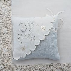 a white pillow with lace and buttons on it sitting on top of a doily