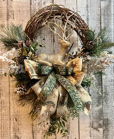 a wreath with deer and pine cones hanging on a wooden wall next to a fence