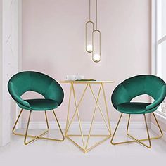 two green chairs sitting in front of a table next to a white wall with gold trim