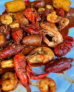 a plate full of shrimp, corn and potatoes on the cob with some seasoning