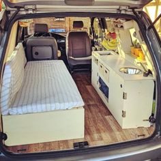 the back end of a van that has a bed in it and an oven inside