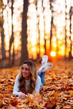 a woman laying on the ground surrounded by leaves