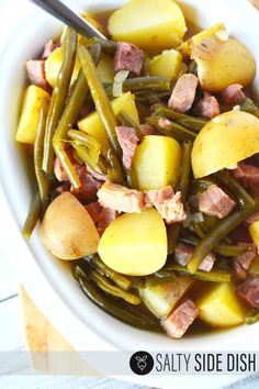 a white bowl filled with green beans, potatoes and ham