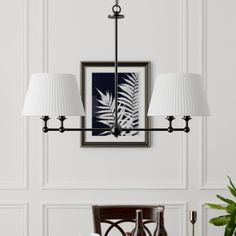 a chandelier hanging over a dining room table with two lamps on each side