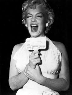 marilyn monroe singing into a microphone with her mouth open and eyes closed, while holding an object in front of her face