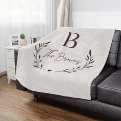 a white blanket with the letter b on it is sitting in front of a couch