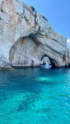 the water is crystal blue and clear, with an arch in the rock face above it