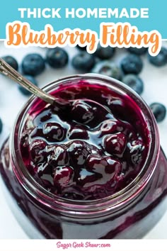 blueberry filling in a glass jar with a spoon on top and berries around it