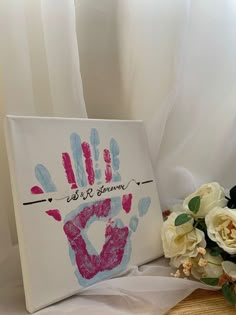 a hand print is on the canvas next to some flowers