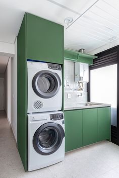 two washers and a dryer in a green kitchen with white counter tops on the walls