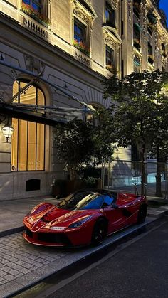 a red sports car is parked on the side of the road in front of a building