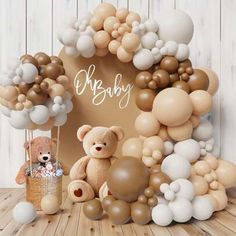 a teddy bear surrounded by balloons in front of a baby's frame with the word oh baby written on it