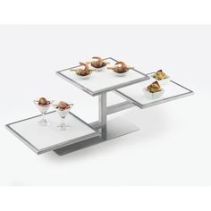 two tables with glass top and metal base, each topped with different types of food