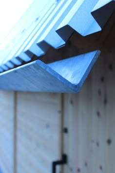 a close up of a metal roof on a wooden building with wood slats in the background