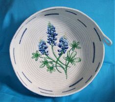 a white bowl with blue flowers painted on the side and green stems in the center