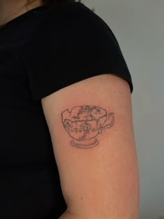 a woman's arm with a small tattoo on it, depicting a teacup