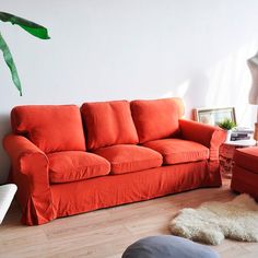 an orange couch sitting in a living room next to a white wall and wooden floor