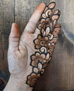 the hand is decorated with henna designs and has an intricate flower pattern on it