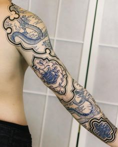 a man with a dragon tattoo on his arm is standing in front of a tiled wall