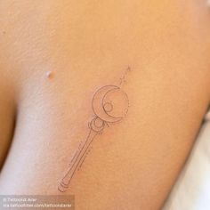 a small tattoo on the back of a woman's left shoulder, with a key in it