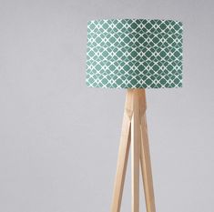 a wooden tripod floor lamp with a green and white lampshade on it