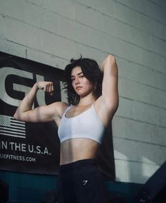 a woman flexing her muscles in front of a gym sign