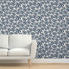 a white couch sitting in front of a wall with blue and white designs on it