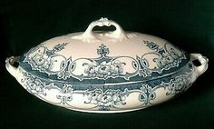 an ornate blue and white covered dish on a black background, with the lid open