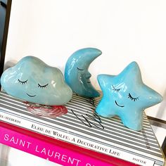 two blue ceramic stars sitting on top of a stack of books next to each other