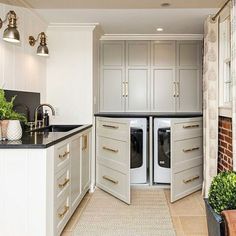 a kitchen with white cabinets and black counter tops, an open washer and dryer