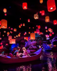 people in a boat with lanterns floating down the river