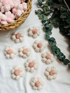 small crocheted flowers sitting on top of a table next to a basket of leaves