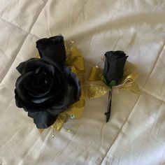 two black roses with gold sequins on them sitting on a white cloth background