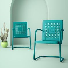 two green chairs sitting next to each other near a potted cacti plant