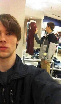 a young man is taking a selfie in front of some clothing mannequins